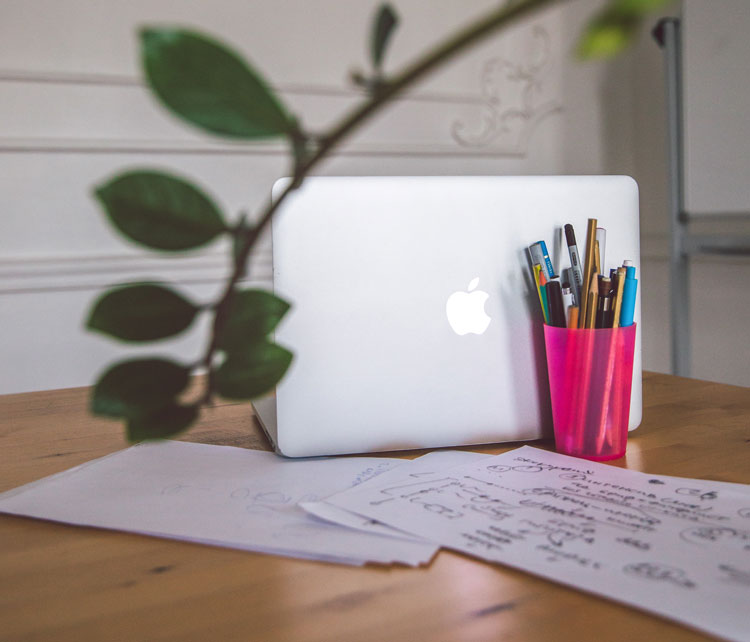 Paprika Creative's desk with macbook pro and sketches of wire frames for website planning